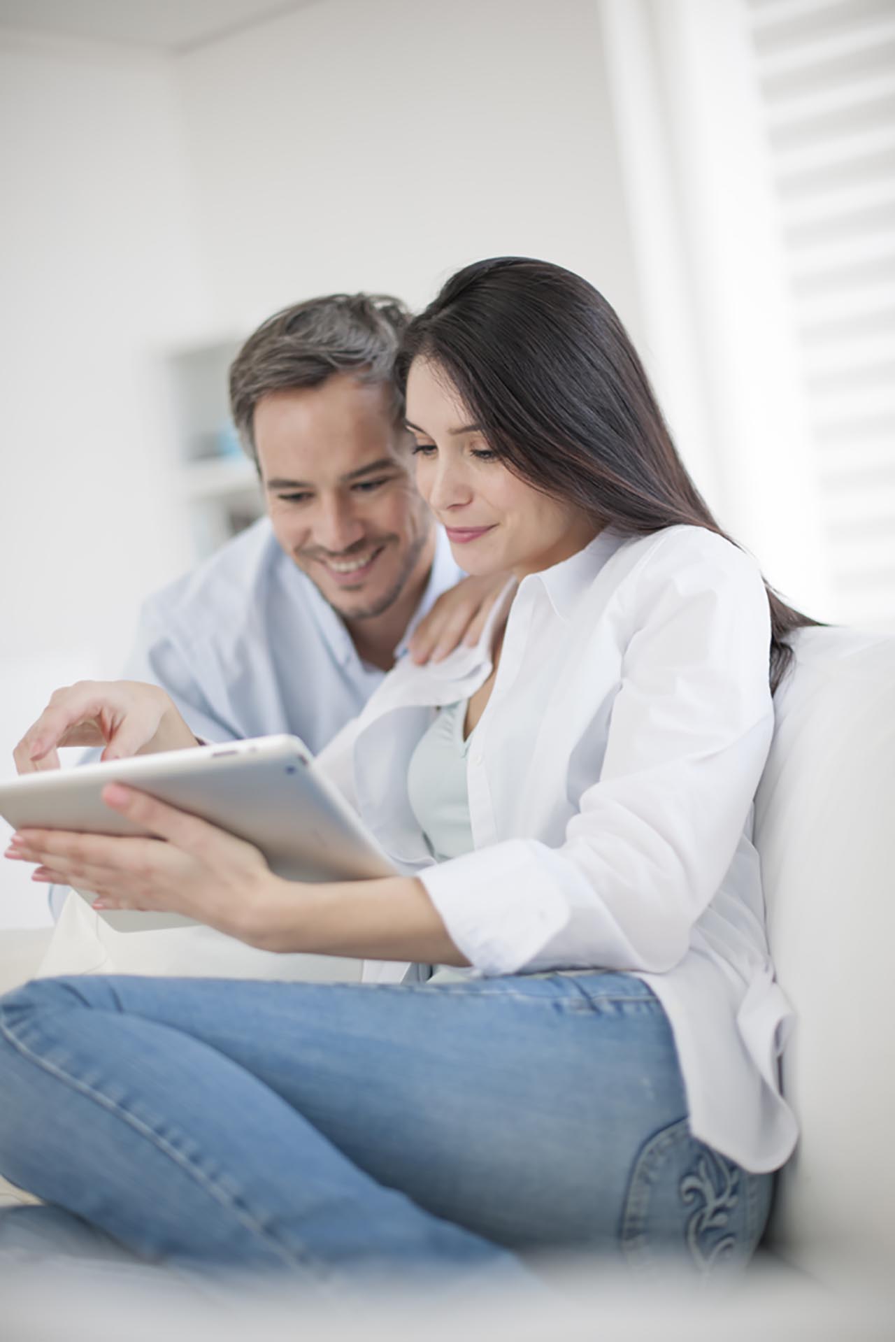 Cheerful couple using digital tablet at hom